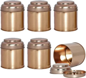 نص بديل: ستة علب شاي أسطوانية أنيقة باللون الذهبي مع أغطية. إحدى العلب مفتوحة، مما يعرض الغطاء والقاعدة بشكل منفصل - مثالية لحفظ أنواع الشاي.