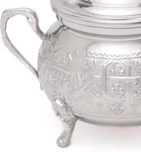 نص بديل: "إبريق شاي فضي مزخرف بنقوش معقدة ومنظر جزئي للمقبض، مثالي لتقديم الشاي على مدونة الشاي.