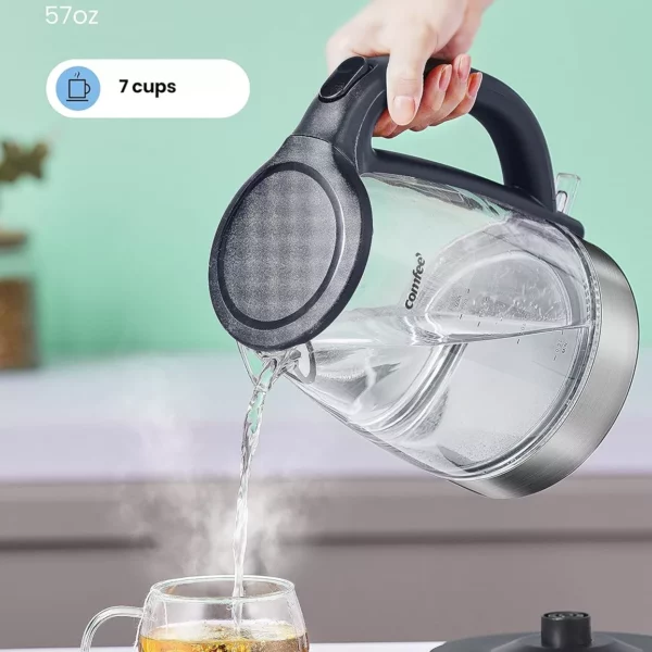 يقوم الشخص بسكب الماء الساخن من غلاية كهربائية سعة 1.7 لتر في فنجان شاي زجاجي باستخدام مصفاة الشاي، جاهزًا للاستمتاع بشاي المفضل لديه.