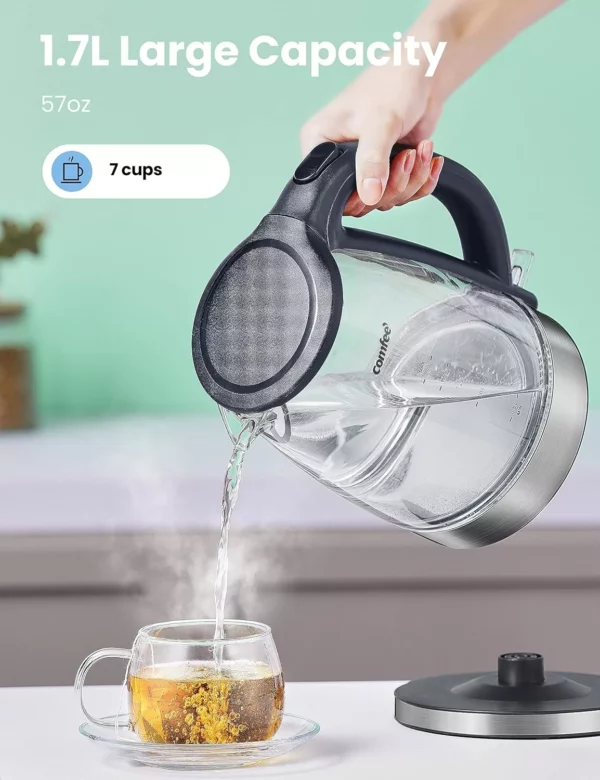 يقوم الشخص بسكب الماء الساخن من غلاية كهربائية سعة 1.7 لتر في فنجان شاي زجاجي باستخدام مصفاة الشاي، جاهزًا للاستمتاع بشاي المفضل لديه.