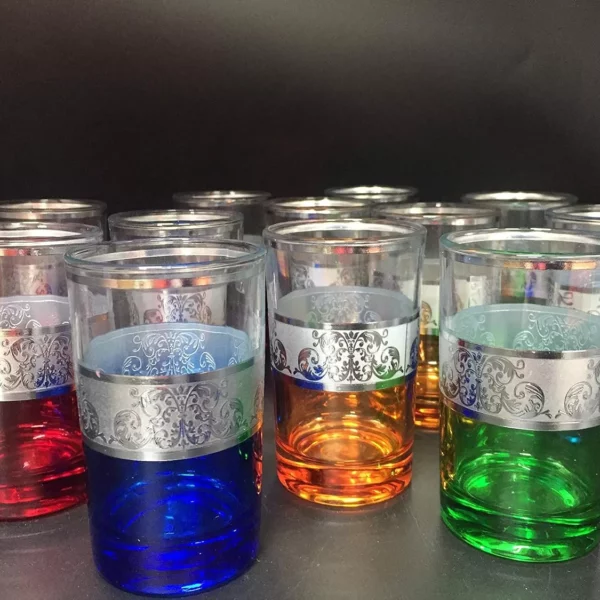 أكواب نابضة بالحياة مزينة بتصميمات فضية معقدة، مرتبة بشكل أنيق في صفوف، مثالية لتقديم أنواع مختلفة من الشاي. تأتي الأكواب بمجموعة متنوعة من الألوان بما في ذلك الأحمر والأزرق والأخضر والبرتقالي.